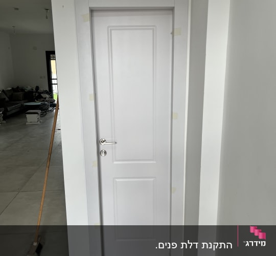 דלת לבנה עם ידית כסופה ומסגרת פשוטה